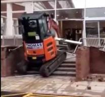 Angry construction worker rams a brand new hotel with excavator
