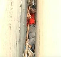 Frightening: man hours clamp in narrow gap between buildings